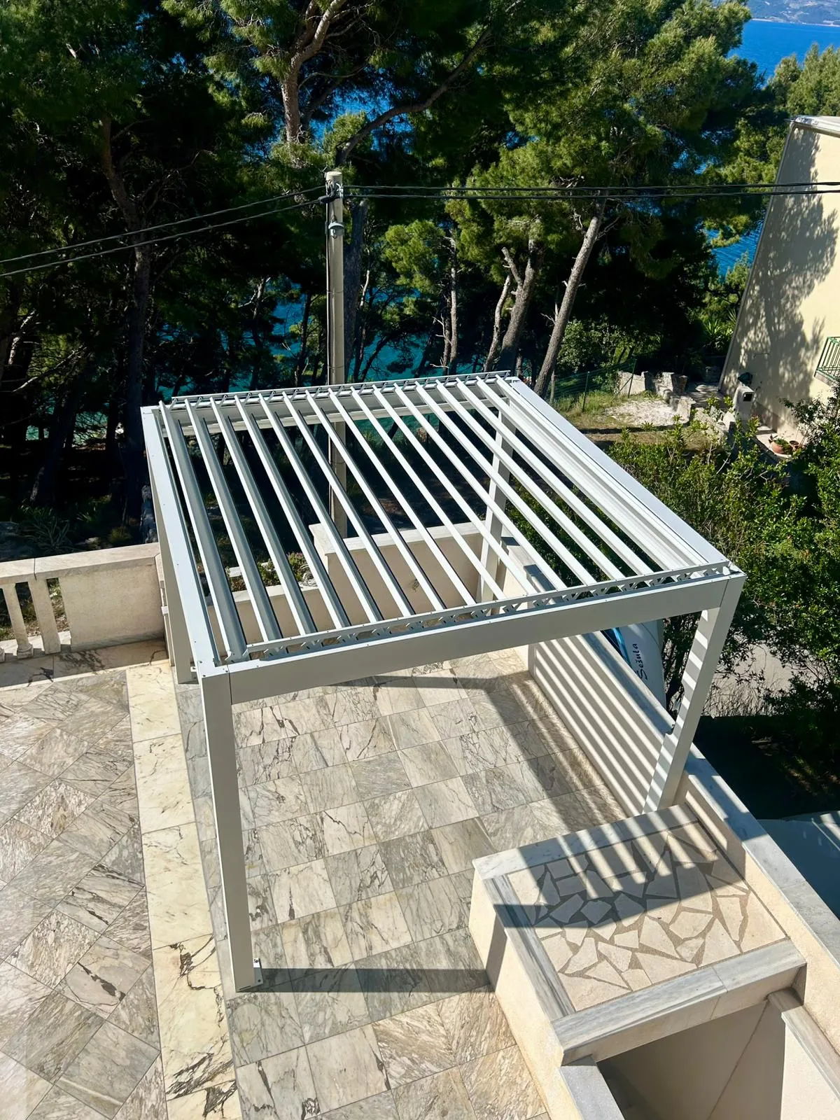 PergoMaxx pergola — kompaktna instalacija na obalnoj terasi s pogledom na more